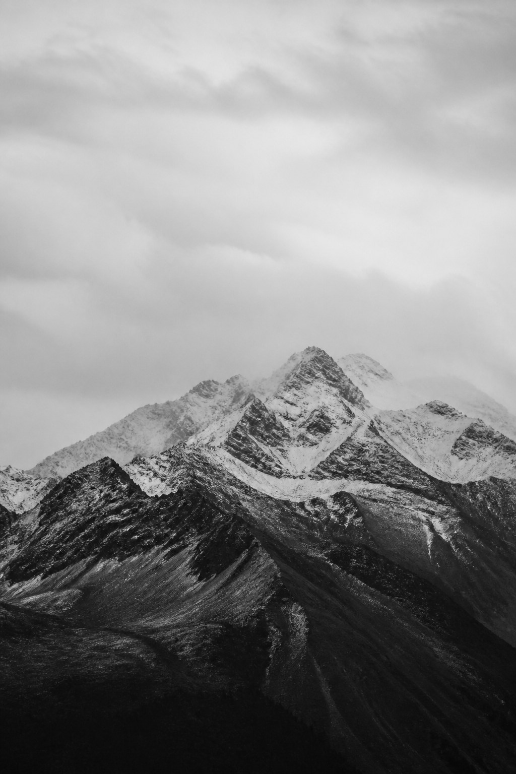 Black-and-white mountain range under low cloud.